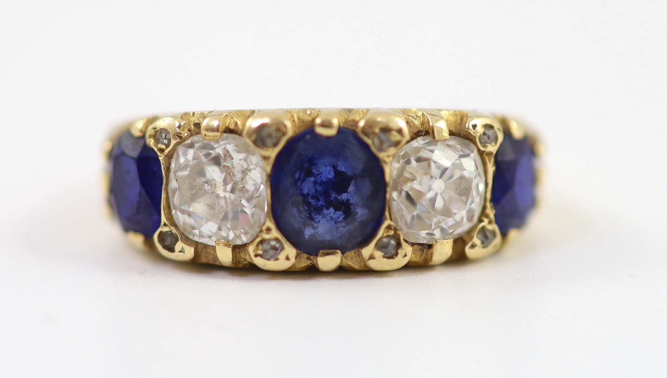 An early 20th century 18ct gold, three stone sapphire and two stone diamond set half hoop ring